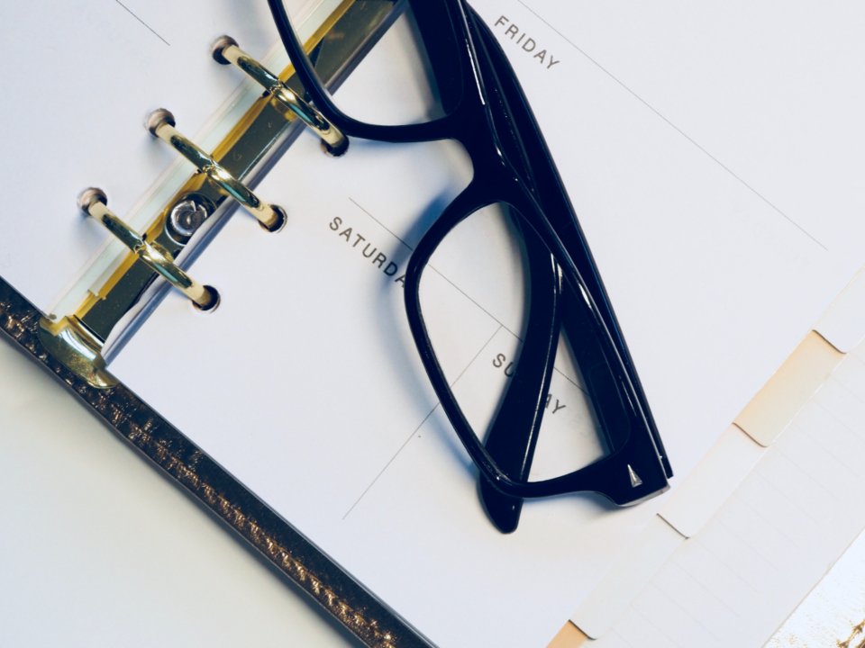 Agenda aberta nos dias da semana, com um par de óculos sobre as páginas