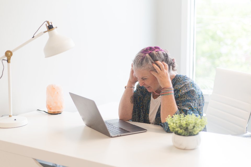 Profissional com as mãos na cabeça, estressada diante do notebook